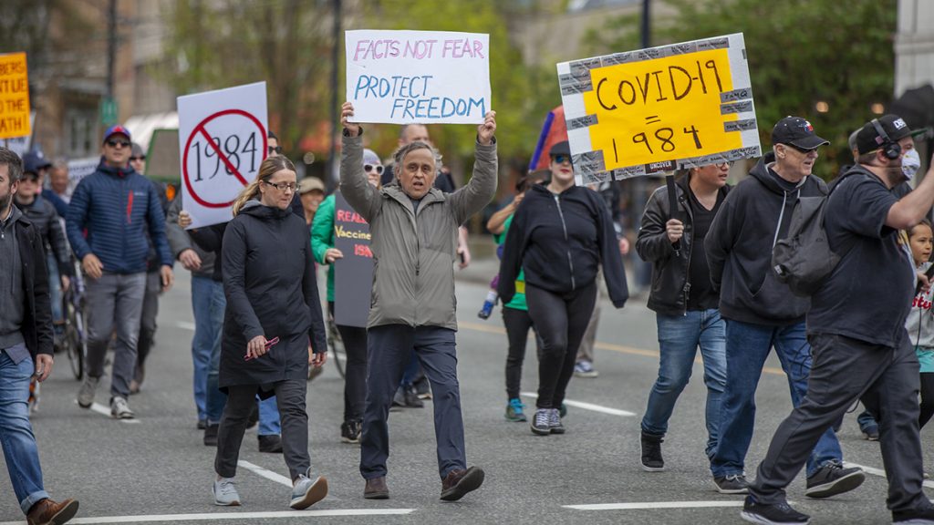Protest against Covid-19 restrictions in Vancouver, Canada on April 26, 2020. People walking down the street with signs that read "Facts not fear. Protect freedom" and "Covid-19=1984"